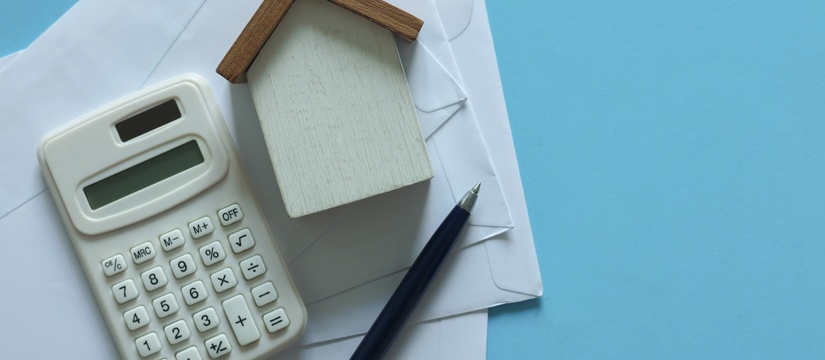 View of home model, pen, calculator, and letters.