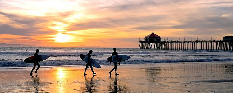 Huntington Beach, California, surfers at sunset near pier