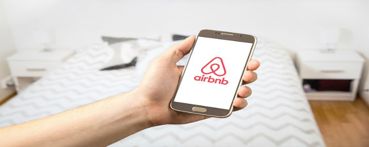 hand holding mobile phone with airbnb app opened