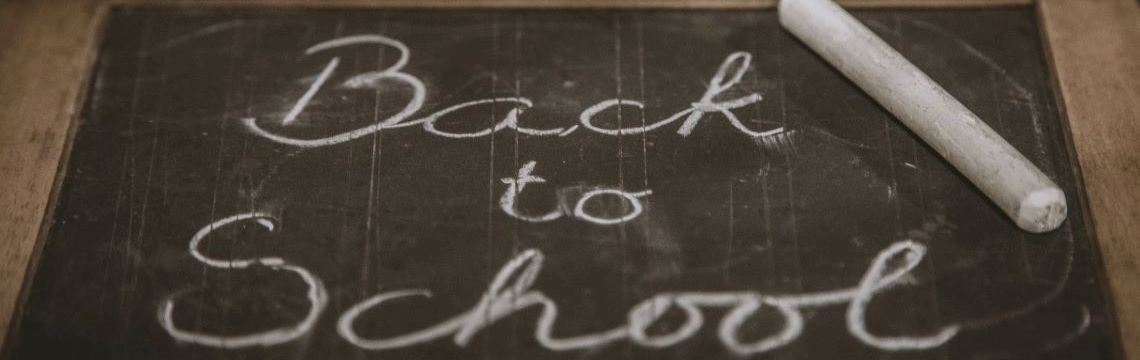 Back to school written on small chalkboard, next to a piece of white chalk.