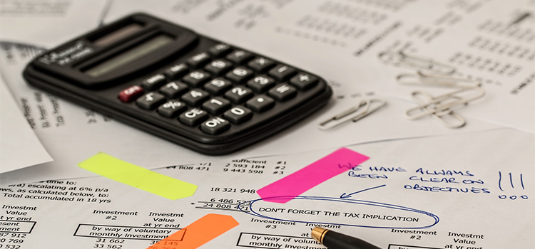 calculator and sticky labels pointing out tax implications on an invoice