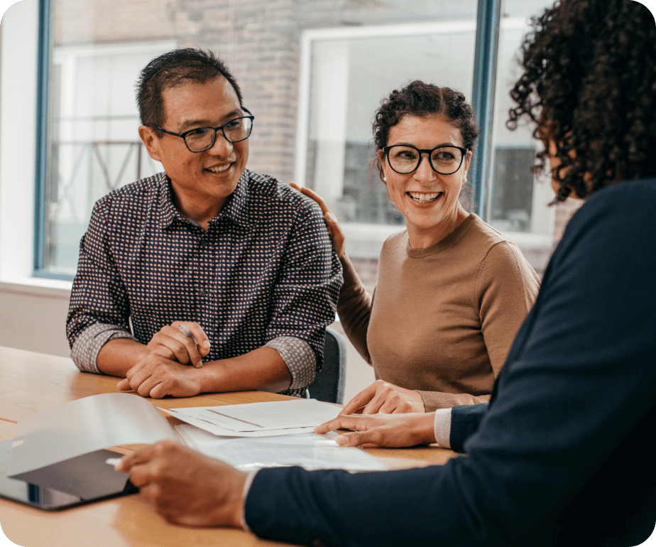 Due persone sedute a un tavolo con documenti, impegnate in una discussione con un consulente.