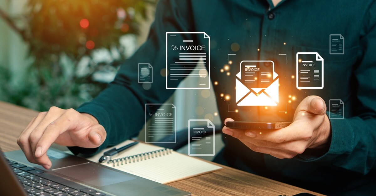 Person working on a computer and holding virtual renditions of invoices in one hand