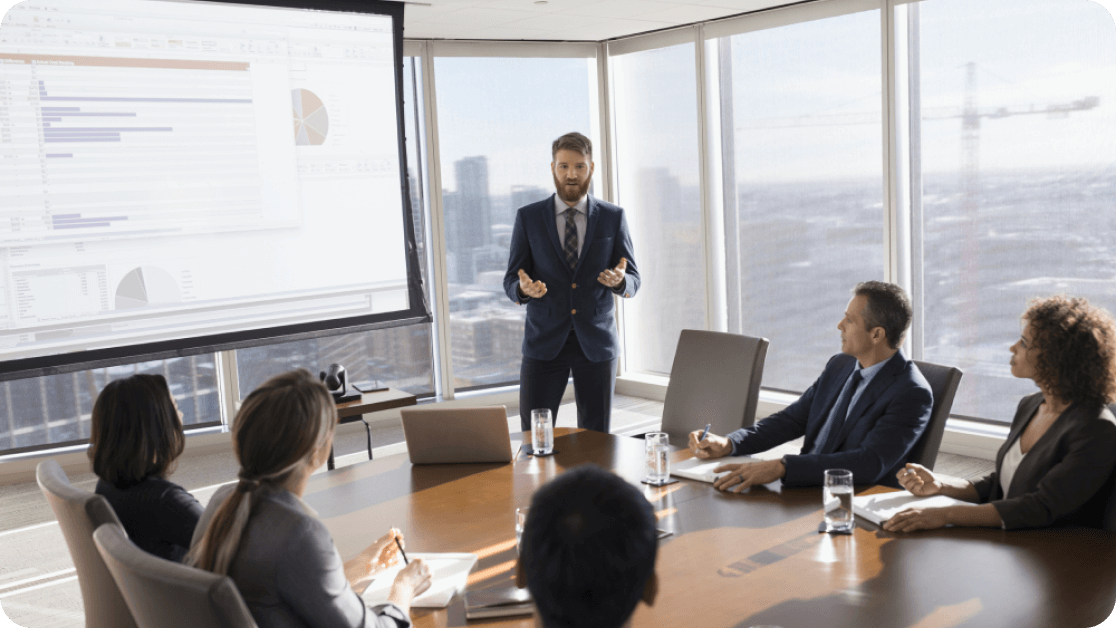 Person presenting to a group of businesspeople in a high-rise conference room.