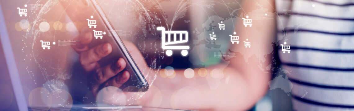 Mobile device laptop online shopping Person with laptop holding mobile device; graphic of online shopping cart