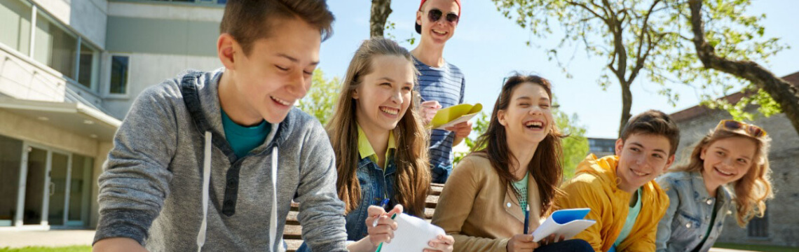 students sitting outside with notebooks
