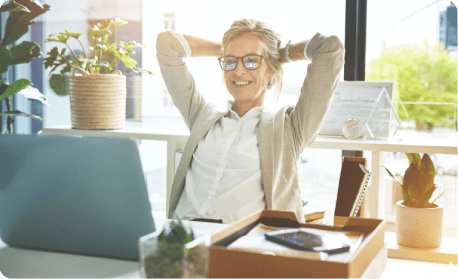 Woman sat smiling at her desk, reclined in her office chair with relaxed expression